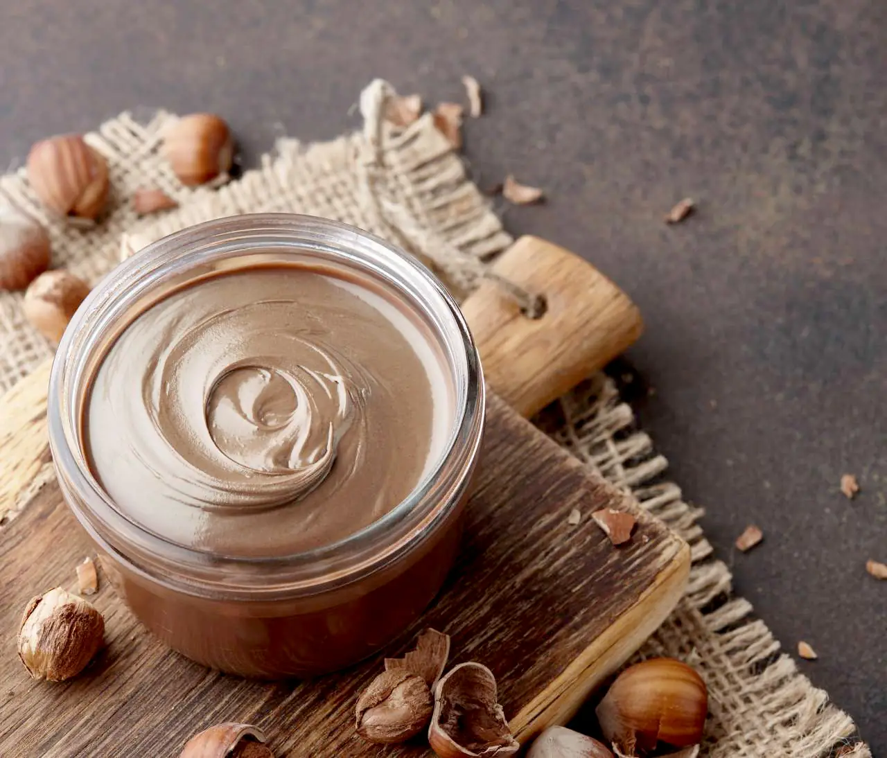 Una ciotola di crema di nocciole circondata da nocciole intere
